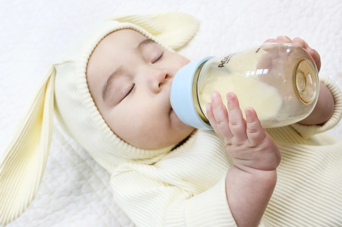 Em bé ngậm núm vú bình sữa, minh họa lý do không nên cho trẻ bú bình không có sữa