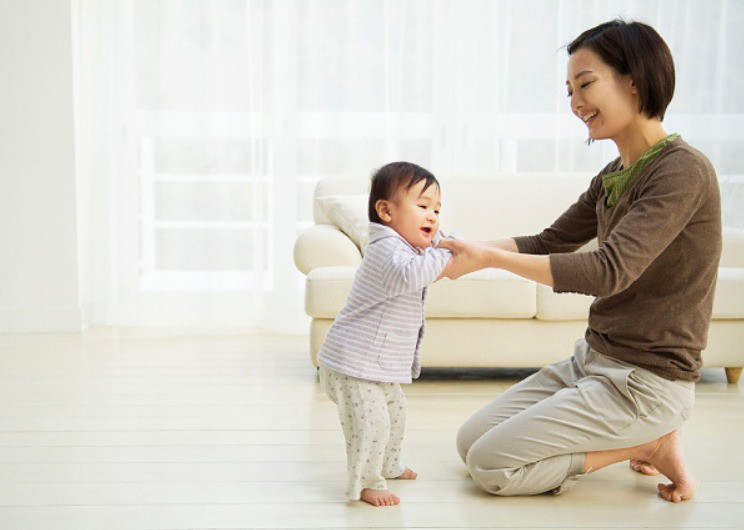 Bé đang tập đứng lên từ tư thế ngồi, minh họa phương pháp tập đi cho bé tự nhiên và an toàn