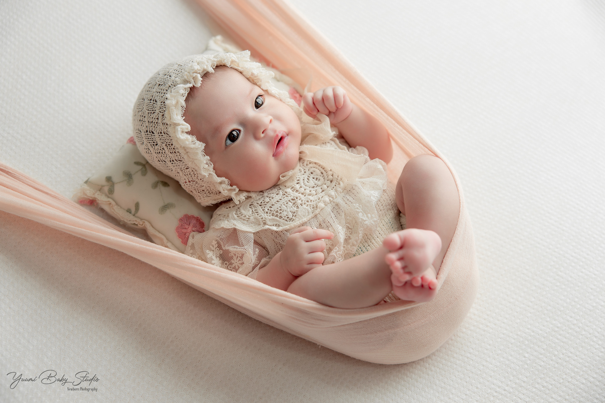 Bé gái ngồi trên phao bơi hình vòng tròn màu hồng, cười vui vẻ