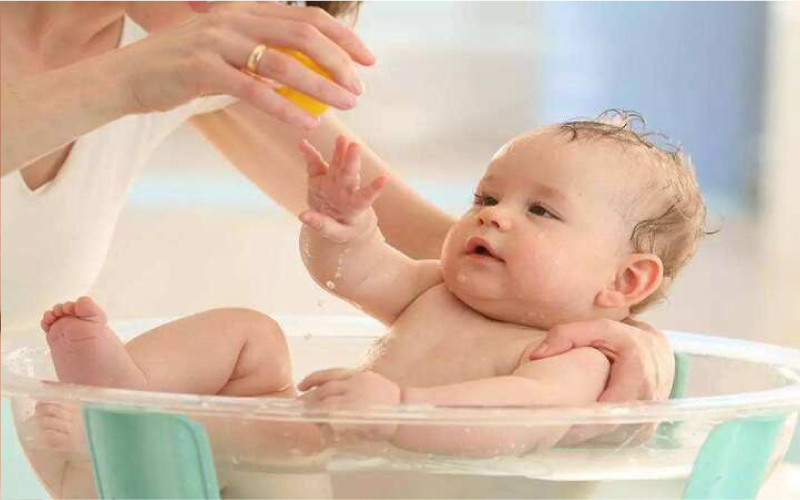 Hình ảnh em bé tắm và giữ ấm cơ thể với dầu tràm