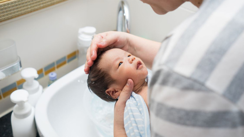 Hình ảnh một em bé nằm ngửa, cho thấy trẻ bị méo đầu có tròn lại được không khi can thiệp sớm.
