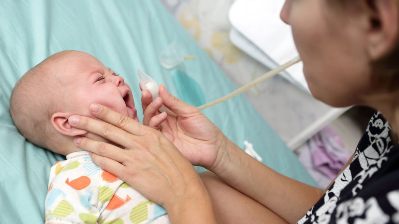 Hình ảnh một phụ huynh nhẹ nhàng rửa mũi cho trẻ sơ sinh 1 tháng tuổi, minh họa quy trình vệ sinh an toàn và hiệu quả
