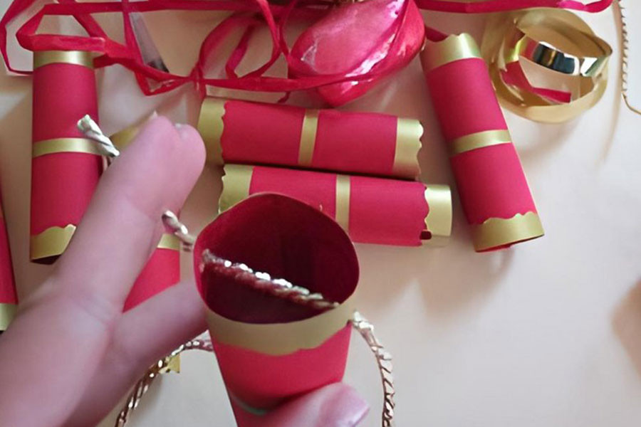 Luồn dây ruy băng qua các ống pháo hoa bằng giấy để tạo thành dây pháo trang trí.