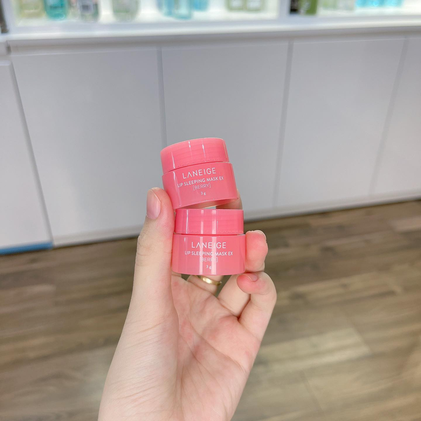 Mặt nạ ngủ Laneige màu hồng được đặt trên một bề mặt cùng với một bông hoa hồng và các loại quả mọng tươi, tạo bối cảnh thiên nhiên