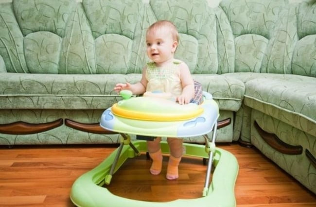 Một bé sơ sinh đang sử dụng xe tập đi tròn, loại xe truyền thống thường gây tranh cãi về việc có nên cho bé ngồi xe tập đi sớm hay không.