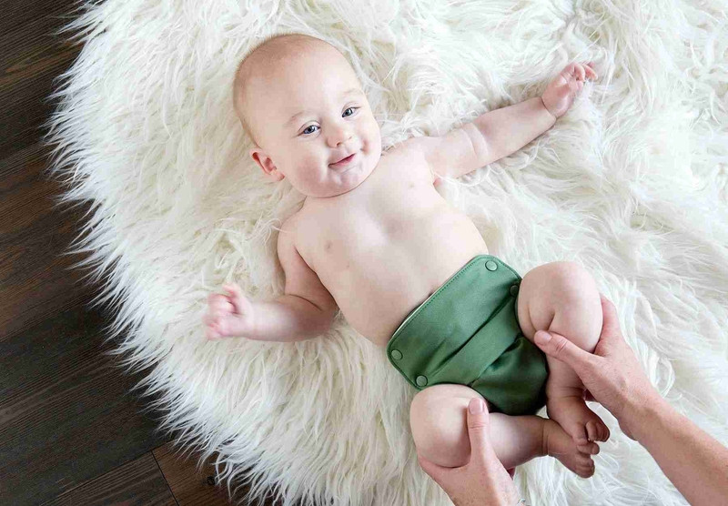 Một em bé đang nằm chơi vui vẻ, minh họa sự thoải mái khi dùng bỉm vải, giải đáp thắc mắc dùng bỉm vải cho bé có tốt không