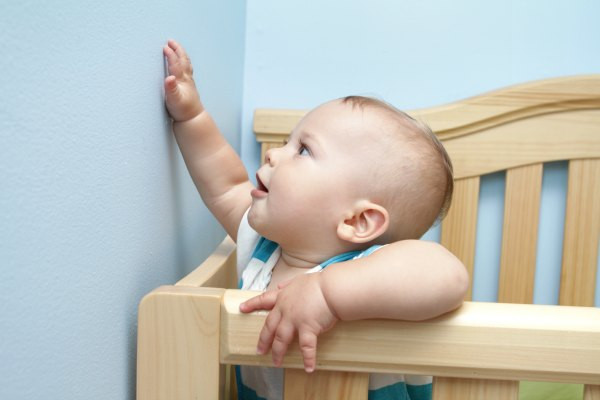 Bé 8 tháng tuổi vịn vào ghế sofa để đứng lên, minh họa sự phát triển vận động của trẻ 8 tháng tuổi trong việc tập đi