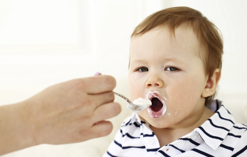 bé gái vui vẻ đang thưởng thức váng sữa, minh họa độ tuổi váng sữa mấy tháng ăn được