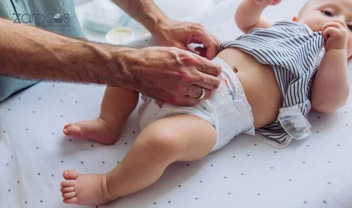 Bé ngủ say trong nôi với chiếc bỉm hơi đầy, cho thấy sự thoải mái nhưng vẫn cần kiểm tra tình trạng bỉm.