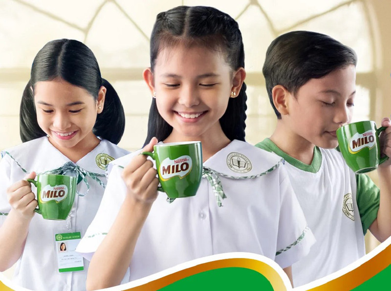 Bé trai cầm hộp Milo với nụ cười, minh họa thắc mắc uống Milo có tăng chiều cao không của nhiều phụ huynh.