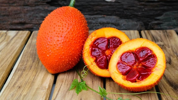 Bổ đôi quả gấc chín để lấy hạt gấc làm dầu tại nhà