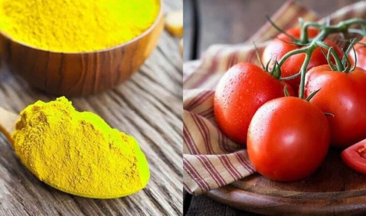 Bột tinh bột nghệ màu vàng và cà chua đỏ tươi trên nền gỗ, thể hiện nguyên liệu cho công thức làm sáng da với cà chua và nghệ.