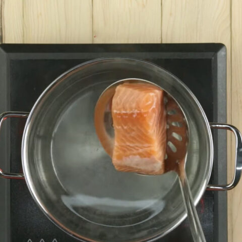 Cá hồi đang được luộc sơ để nấu cháo cá hồi bí đỏ