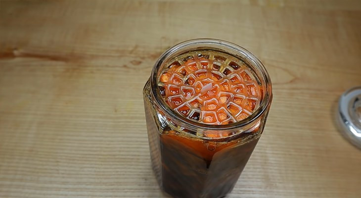 Đổ mật ong vào hũ chứa nghệ thái lát, thực hiện cách làm mật ong ngâm nghệ