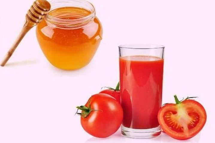 Hũ mật ong nguyên chất cùng thìa gỗ, ly nước ép cà chua tươi và quả cà chua cắt đôi, tượng trưng cho công thức tắm trắng bằng cà chua và mật ong.