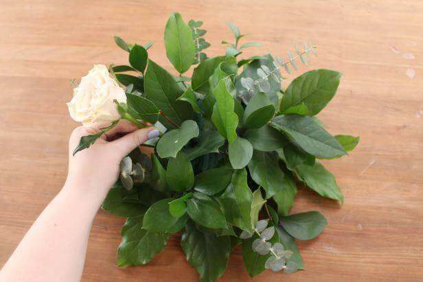 Một bó hoa hồng màu hồng nhạt được cắm gọn gàng trên bàn, cho thấy một trong những cách cắm hoa hồng đơn giản mà đẹp