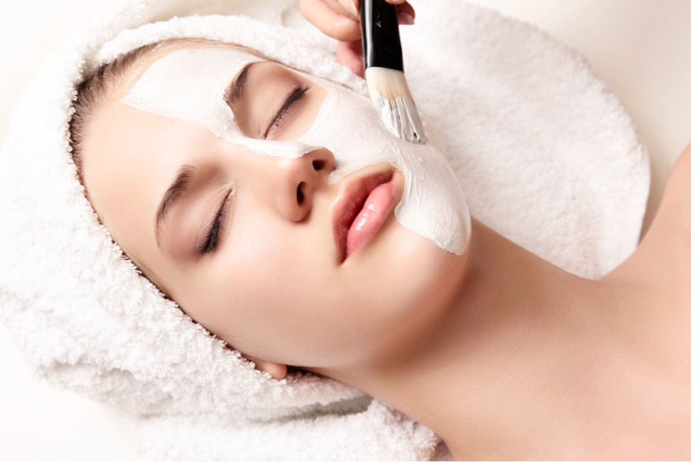 Một người phụ nữ đang xem đồng hồ khi đắp mặt nạ, đặt câu hỏi về thời gian dùng mặt nạ tốt nhất hiện nay