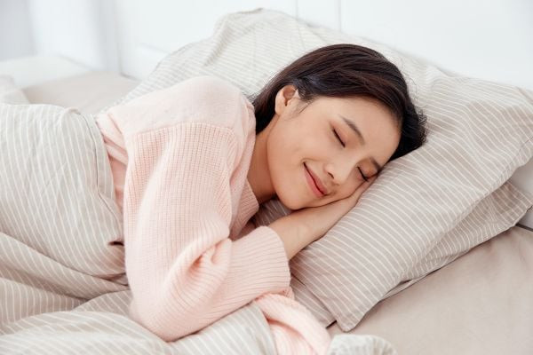 Một người phụ nữ nằm thư giãn trên giường sau khi xông hơi, minh họa việc nghỉ ngơi hợp lý để phục hồi sức khỏe.