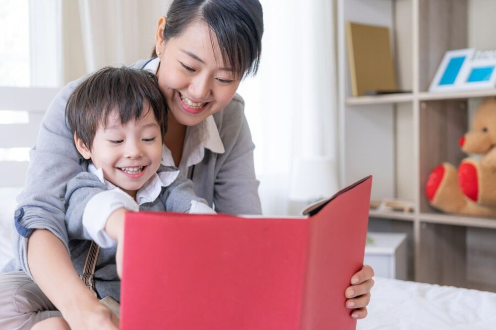 Một phụ huynh đang đọc truyện cho bé nghe một cách chăm chú, góp phần chuẩn bị cho bé đi học mẫu giáo bằng cách phát triển ngôn ngữ và tư duy.