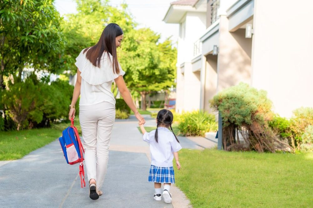 Một phụ huynh đang ôm con tạm biệt tại cổng trường, hình ảnh biểu trưng cho kinh nghiệm ngày đầu tiên đi học mẫu giáo.