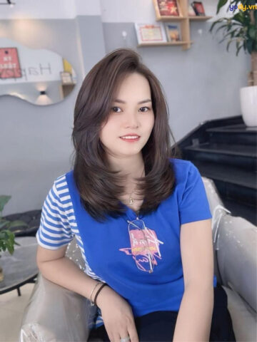 Người phụ nữ đang sử dụng lược điện để làm thẳng tóc tại nhà
