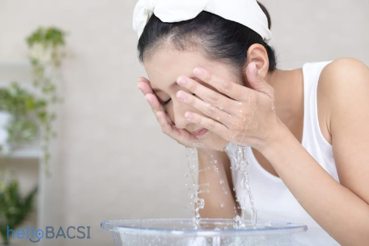 Người phụ nữ rửa mặt bằng nước muối sinh lý để làm sạch da