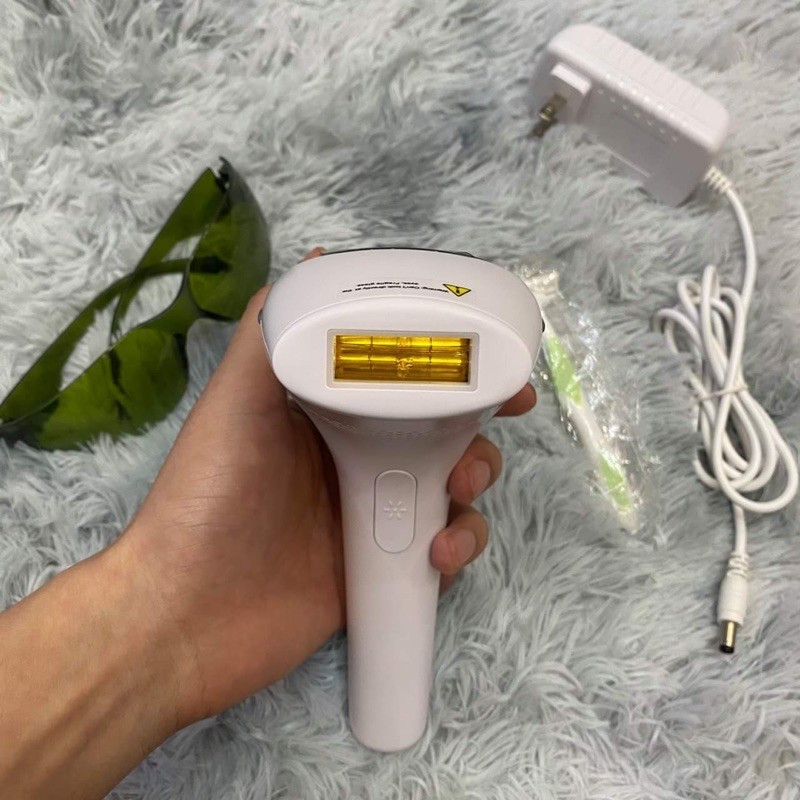 Người phụ nữ trẻ đang sử dụng máy triệt lông mini tại nhà để làm đẹp vùng chân, thể hiện sự tiện lợi và riêng tư của thiết bị.