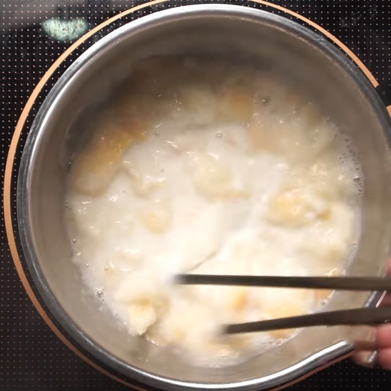 Thêm bánh mì đã xé vụn vào nồi nước đang sôi để nấu cháo bánh mì
