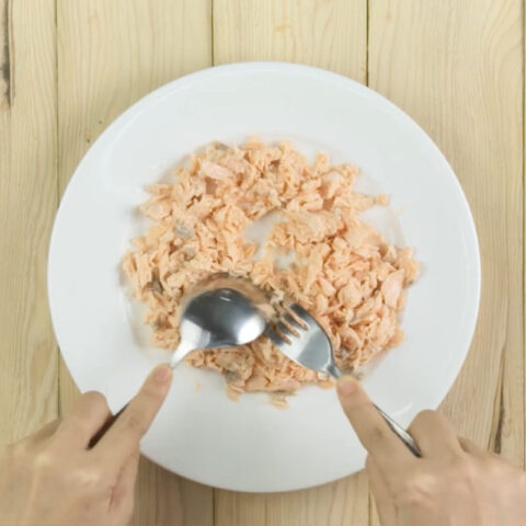 Thịt cá hồi đã được tách nhỏ sau khi luộc để nấu cháo cá hồi bí đỏ
