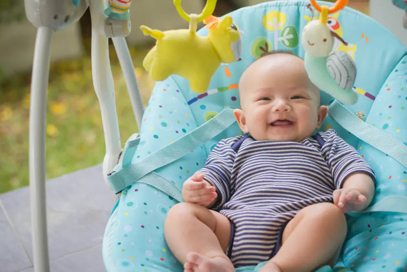 Trẻ sơ sinh thích thú với đồ chơi treo trên ghế nhún giúp kích thích giác quan